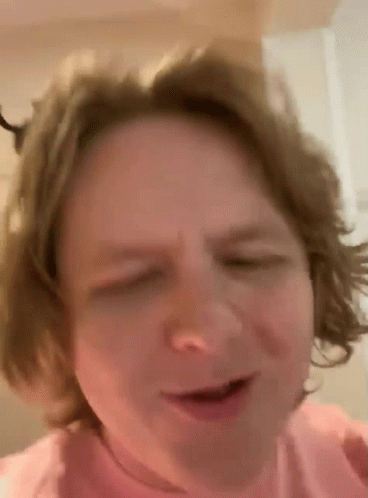 A Close Up Of A Person 'S Face With Their Eyes Closed And Their Hair Blowing In The Wind . GIF