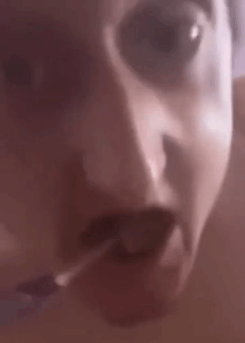A Close Up Of A Person 'S Face With Their Mouth Open And A Cigarette In Their Mouth . GIF