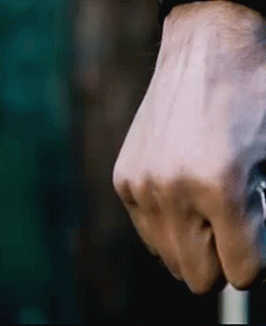 A Close Up Of A Person 'S Fist Holding A Cane In A Dark Room . GIF