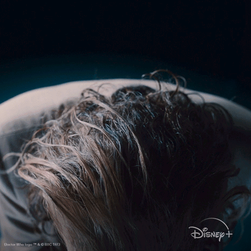 A Close Up Of A Person 'S Hair With The Disney Logo In The Background GIF