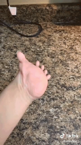 A Close Up Of A Person 'S Hand On A Granite Countertop . GIF