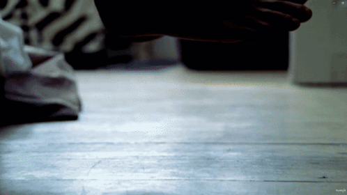 A Close Up Of A Person 'S Hand On A Wood Floor GIF