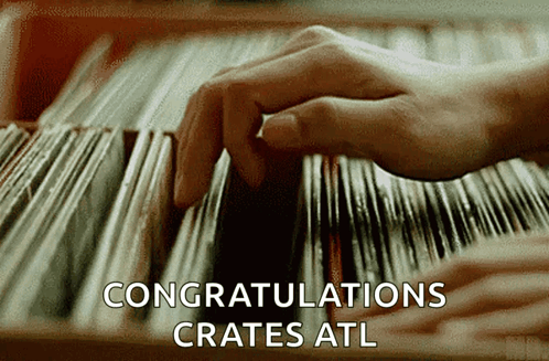 A Close Up Of A Person 'S Hand Picking A Record From A Shelf That Says Congratulations Crates GIF