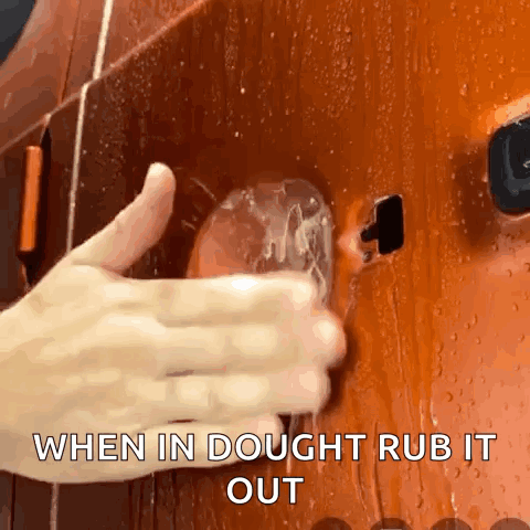 A Close Up Of A Person 'S Hand Rubbing A Glass With The Words When In Dough Rub It Out Below It GIF