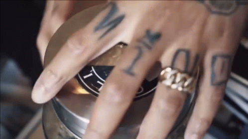 A Close Up Of A Person 'S Hand With Tattoos And A Ring GIF