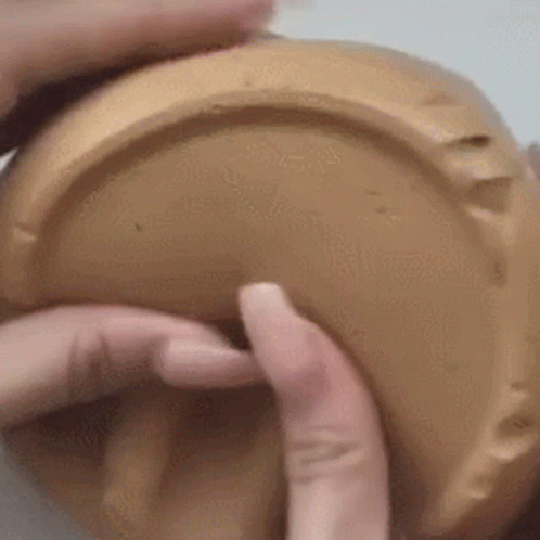 A Close Up Of A Person 'S Hands Holding A Brown Container . GIF