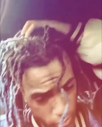 A Close Up Of A Person 'S Head With Dreadlocks And A Purple Background . GIF