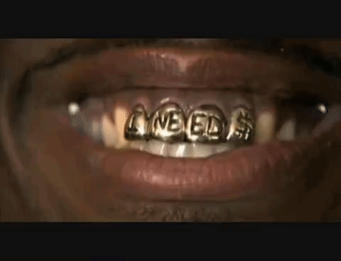 a close up of a person 's mouth with gold teeth grills on it .