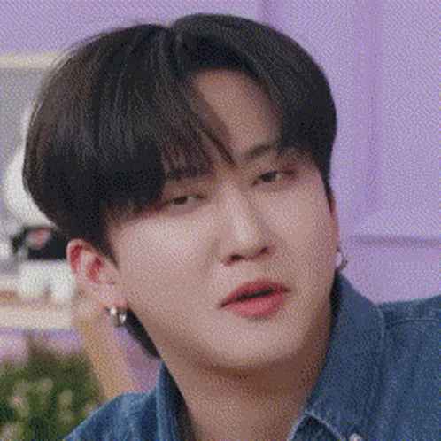 A Close Up Of A Person Wearing A Denim Shirt And Earrings . GIF