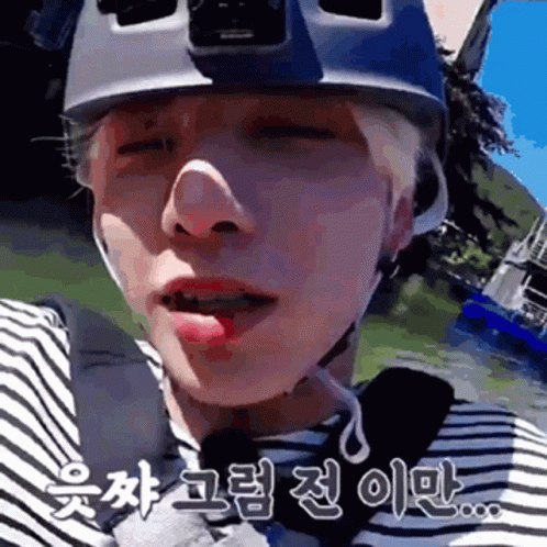 A Close Up Of A Person Wearing A Helmet And A Striped Shirt With Chinese Writing On It . GIF