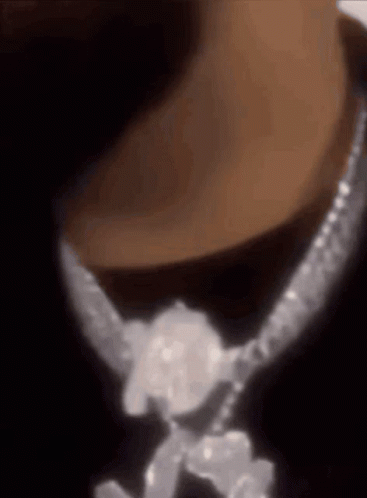 A Close Up Of A Person Wearing A Necklace With Diamonds On It GIF