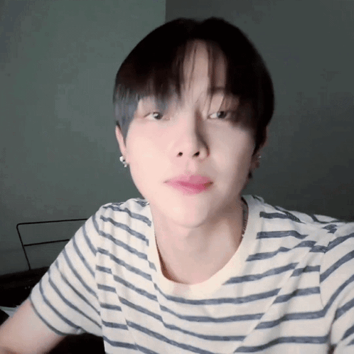 A Close Up Of A Person Wearing A Striped Shirt And Earrings GIF