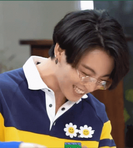 A Close Up Of A Person Wearing Glasses And A Sweater With A Smiley Face On It . GIF