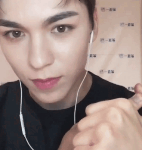A Close Up Of A Person Wearing Headphones And Making A Heart Shape With Their Hands GIF