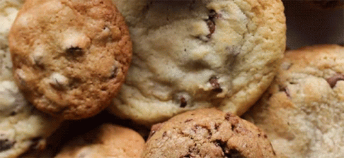 A Close Up Of A Pile Of Cookies Including Chocolate Chip Cookies GIF
