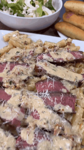 A Close Up Of A Plate Of Food With A Bowl Of Salad In The Background GIF