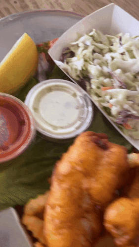 A Close Up Of A Plate Of Food With Coleslaw And A Slice Of Lemon GIF