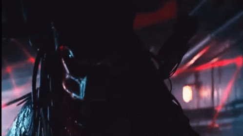 A Close Up Of A Predator In A Dark Room With Red Lights GIF