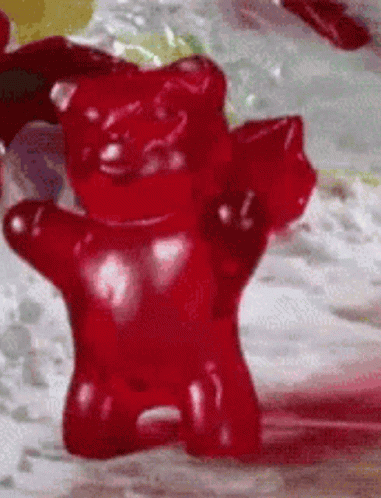 A Close Up Of A Red Gummy Bear On A Table GIF