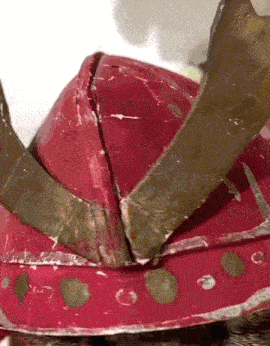 A Close Up Of A Red Helmet With A Crown On It GIF
