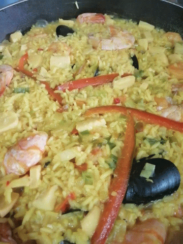 A Close Up Of A Rice Dish With Vegetables And Seafood GIF