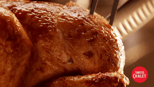 A Close Up Of A Roasted Chicken With Swiss Chalet In The Corner GIF