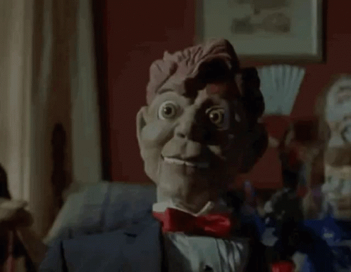 A Close Up Of A Scary Puppet In A Suit And Bow Tie . GIF