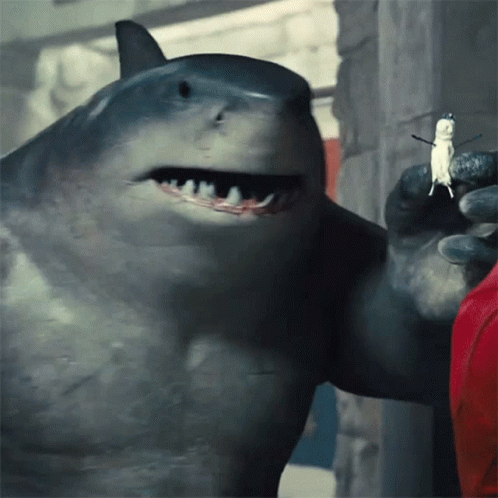 A Close Up Of A Shark Holding A Small Figure In Its Mouth GIF