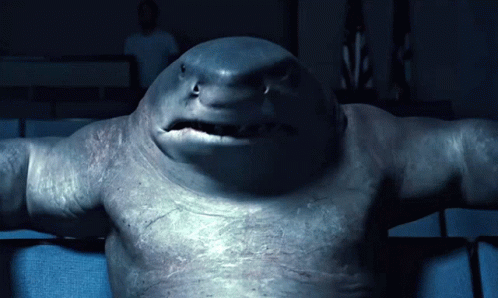 A Close Up Of A Shark 'S Face With A Man In The Background GIF