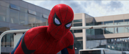 A Close Up Of A Spider Man In Front Of A Large Building GIF
