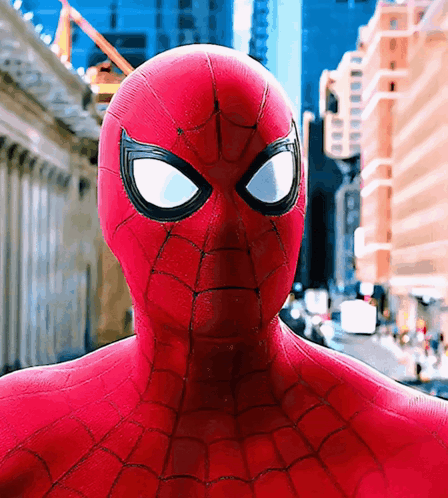 A Close Up Of A Spider Man 'S Face In Front Of A City GIF