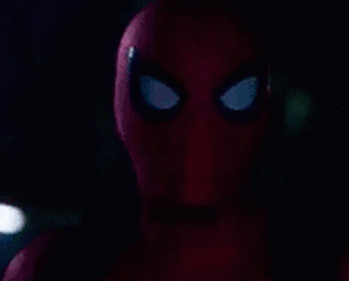 A Close Up Of A Spider-Man 'S Face With A Flashlight In The Background . GIF