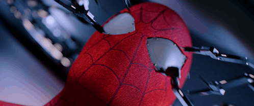 A Close Up Of A Spider Man 'S Face With A Hole In It GIF