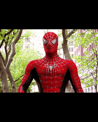 A Close Up Of A Spider Man Standing In Front Of A Building GIF