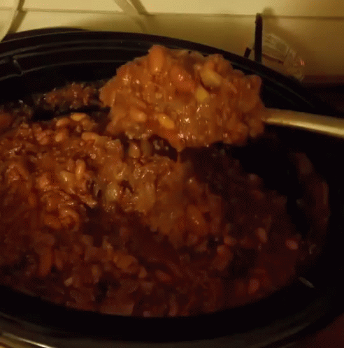 A Close Up Of A Spoon In A Crock Pot Filled With Beans GIF
