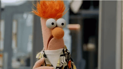 A Close Up Of A Stuffed Animal With Big Eyes And Red Hair Holding A Cup . GIF