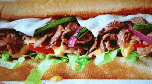 A Close Up Of A Sub Sandwich With Lettuce Tomato And Cheese GIF