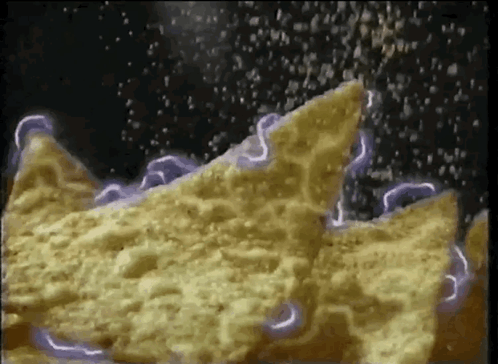 a close up of a tortilla chip being sprinkled with salt