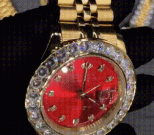 A Close Up Of A Watch With A Red Face And Diamonds GIF