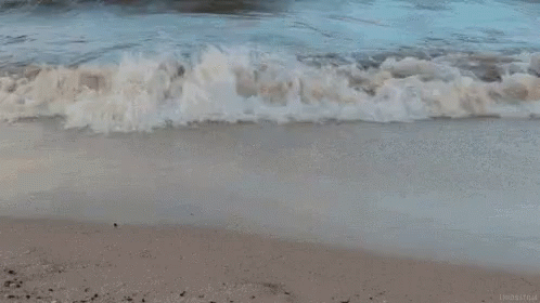 A Close Up Of A Wave Breaking On A Beach . GIF