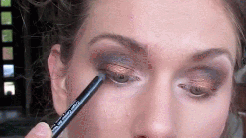 A Close Up Of A Woman Applying Eye Shadow With A Pencil . GIF