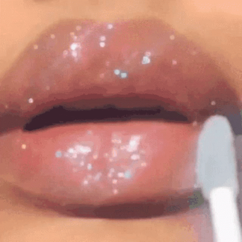 A Close Up Of A Woman Applying Lip Gloss With A Brush . GIF