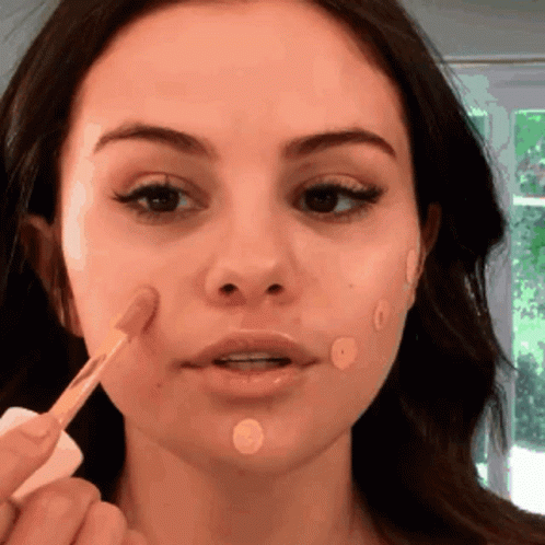 A Close Up Of A Woman Applying Makeup To Her Face GIF