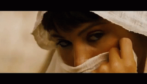 A Close Up Of A Woman Covering Her Face With A White Scarf . GIF