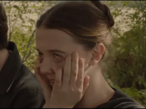 A Close Up Of A Woman Covering Her Face With Her Hand . GIF