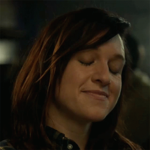 A Close Up Of A Woman Drinking From A Bottle In A Dark Room GIF
