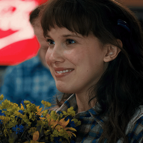 A Close Up Of A Woman Holding A Bouquet Of Flowers And Smiling GIF