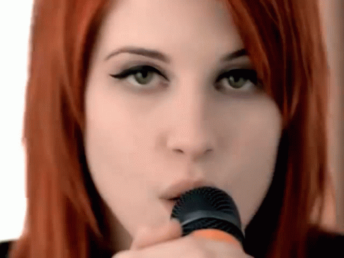 A Close Up Of A Woman Holding A Microphone In Her Mouth . GIF