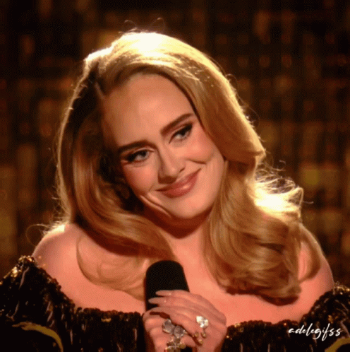 A Close Up Of A Woman Holding A Microphone With The Words Adel / Gifss On The Bottom Right GIF