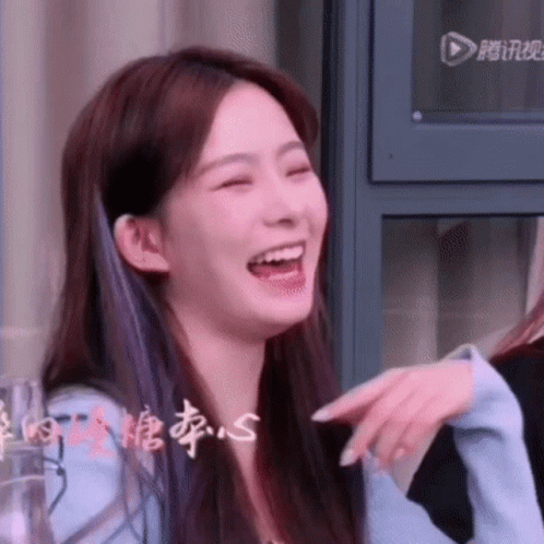 A Close Up Of A Woman Laughing With Her Mouth Open And Pointing At Something . GIF